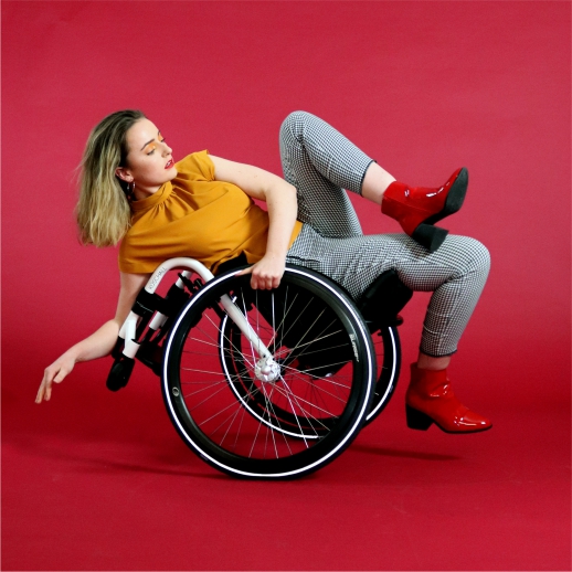 A studio portrait photograph of Maya Leeke with a red background.