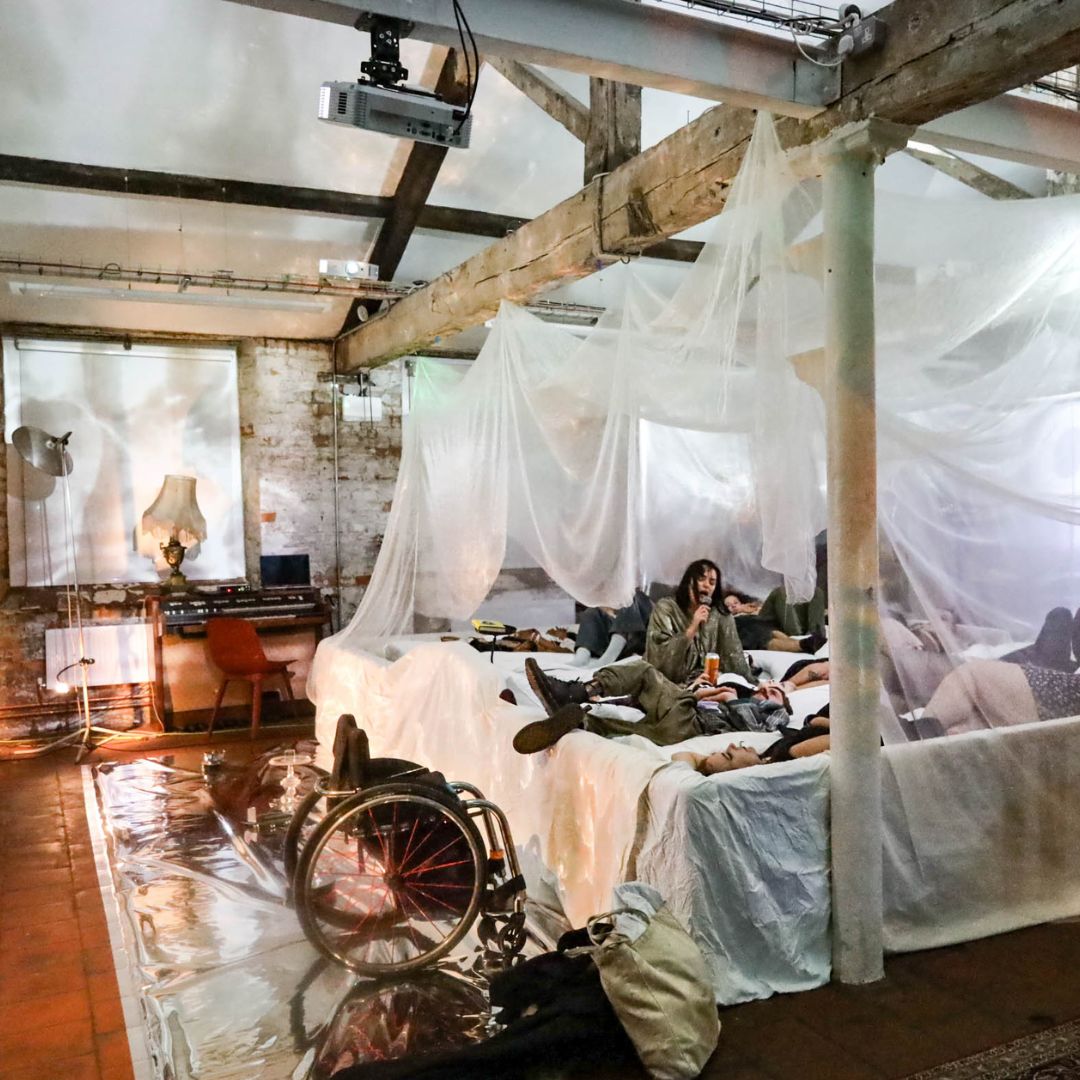 Some people lying down on a bed. They are in a room with wooden beams