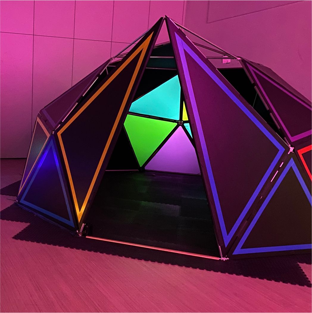 A photograph of the sound play dome. A multi coloured triangular tent like structure, housed in the Level Centre.